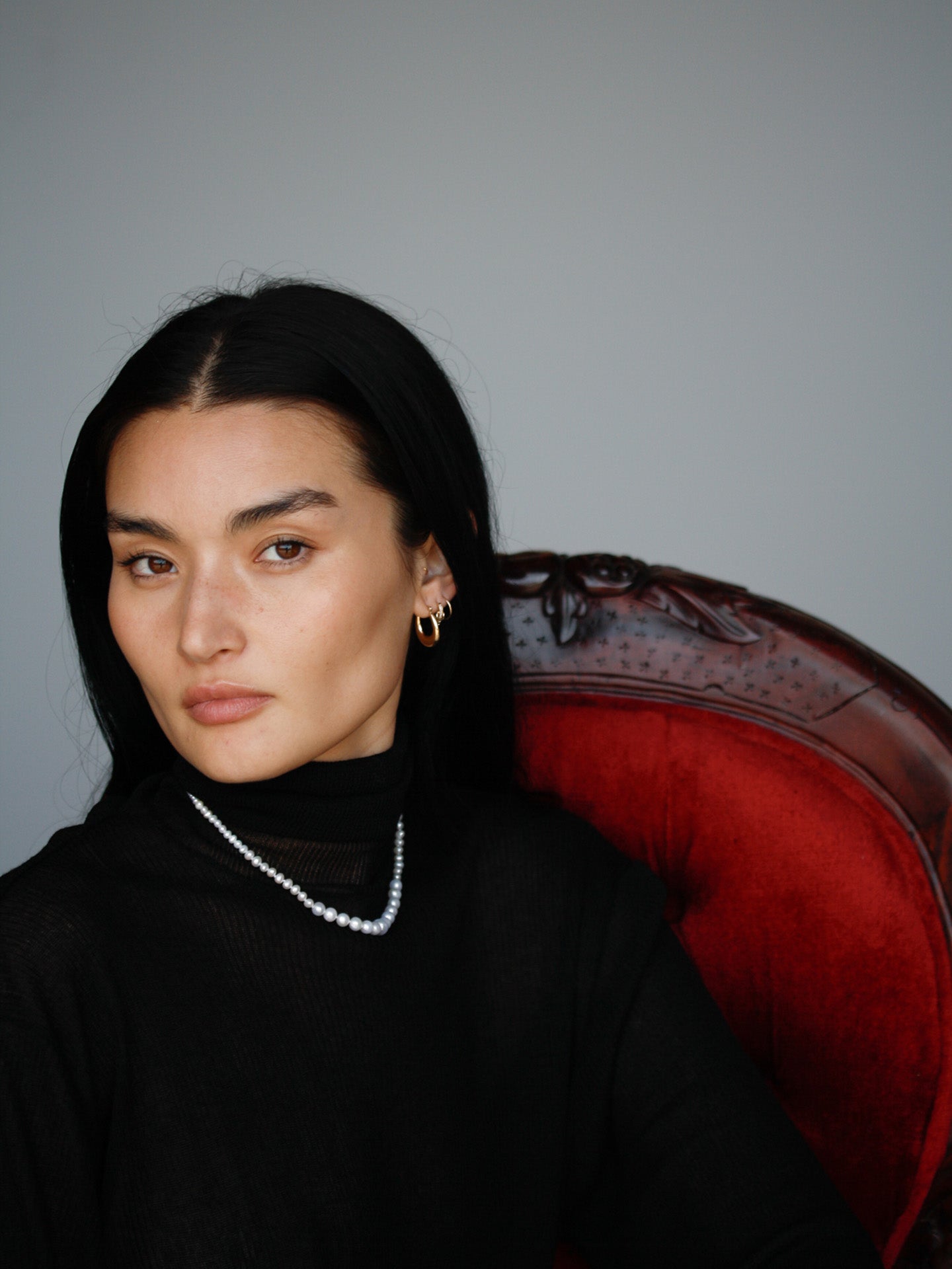 Dome Hammock Hoops pictured on model. Red chair and grey background. 