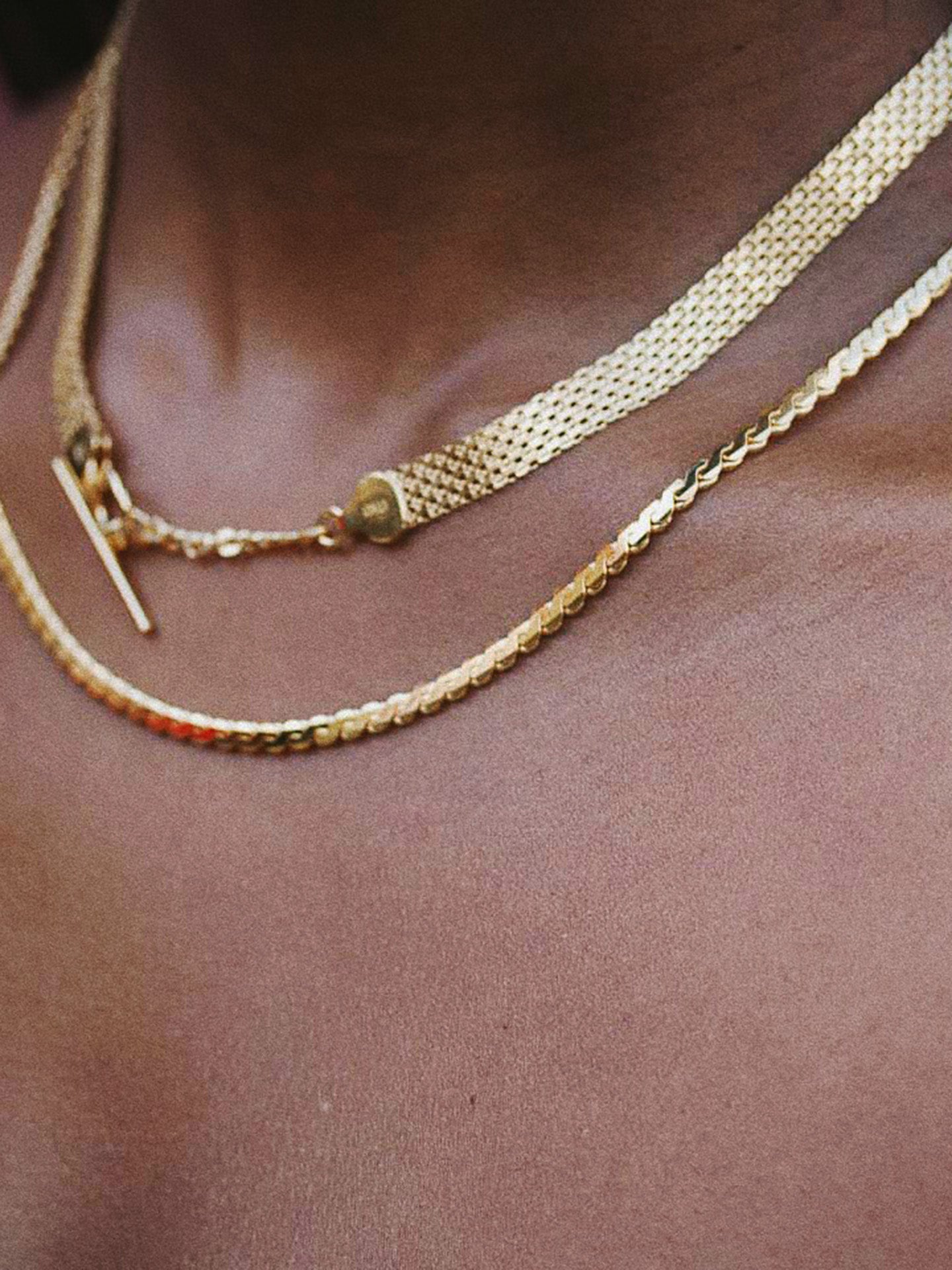 Close up shot of Serpentine Chain pictured on models neck. 18” Length. Paired with the Chainmail Necklace with toggle closure in the front. 