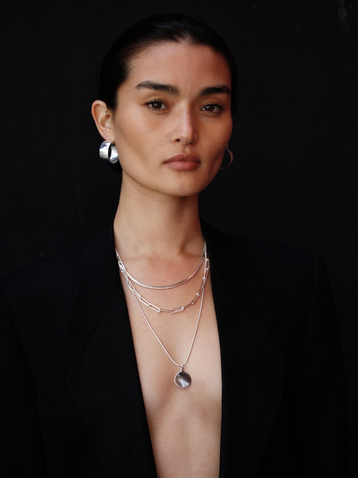 Sterling Silver Disk Pendant pictured on model. Black background. 