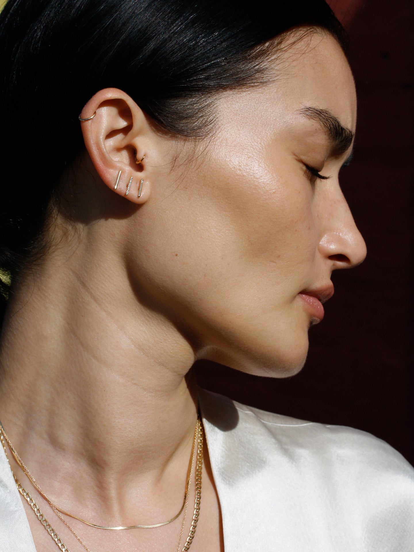Rod stud pictured in models third piercing. Black background. 