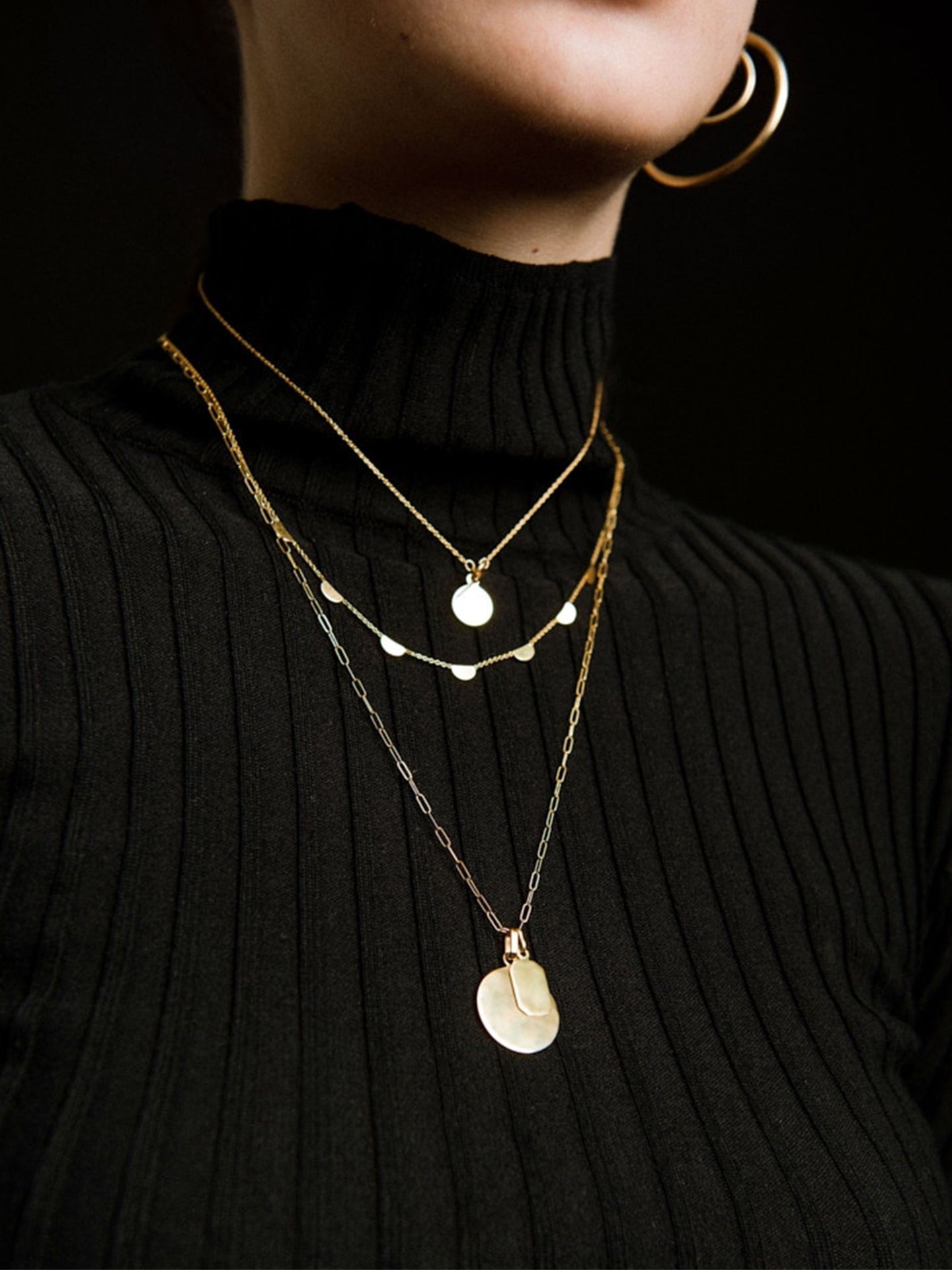 Octagonal ID Pendant pictured laying on top of Disk Pendant strung from chain. Black background. 