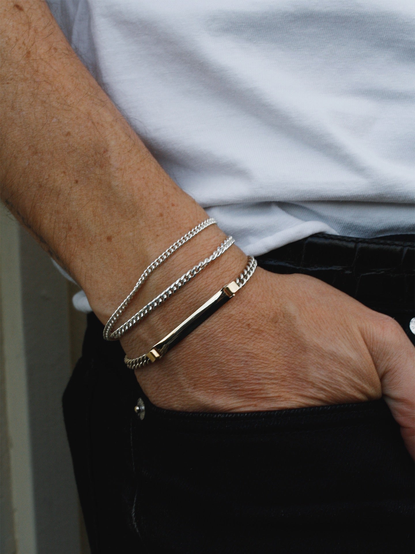 Close-up of a wrist wearing multiple bracelets with a neutral background