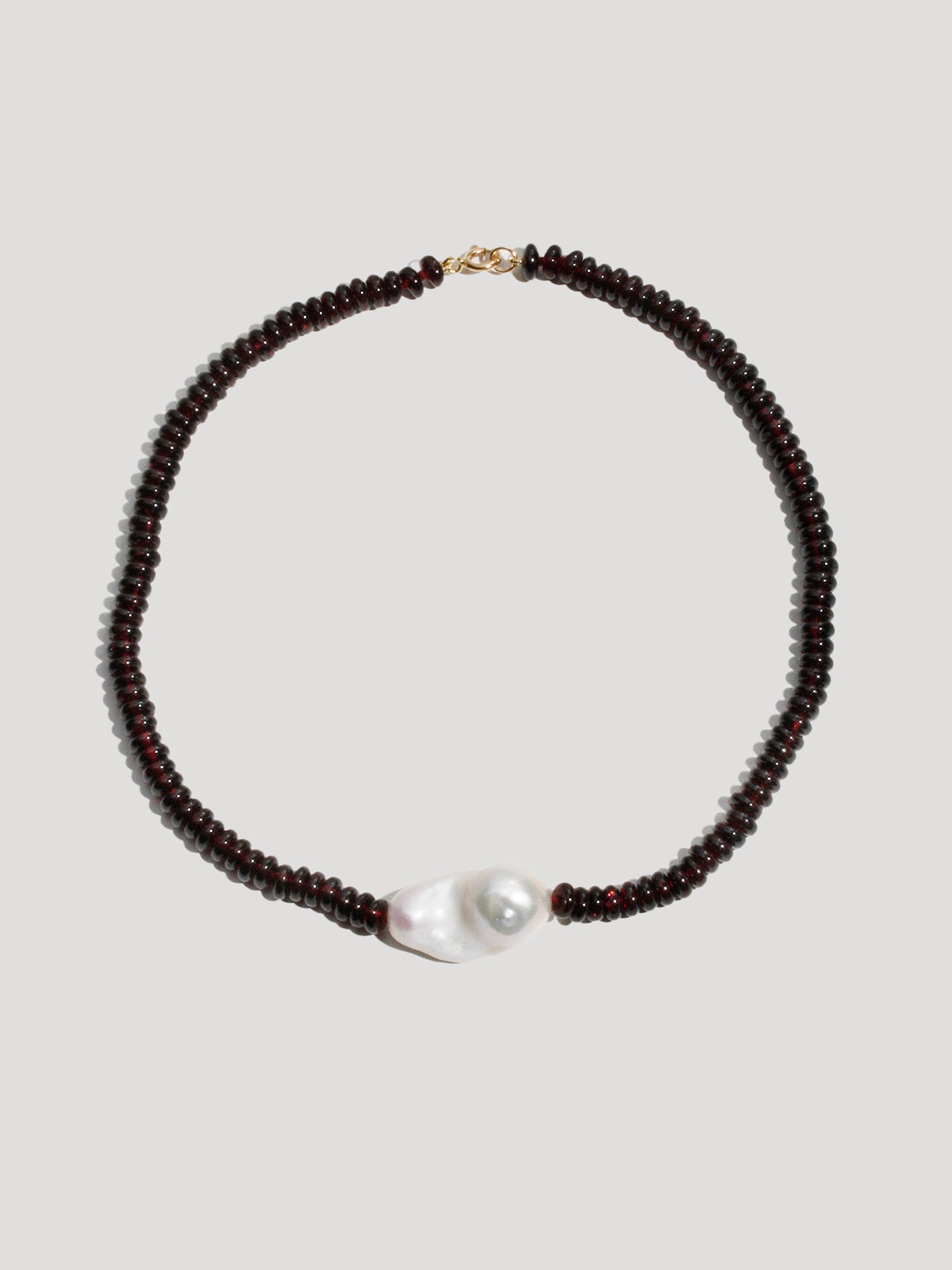 Necklace with dark beads and a pearl on a light gray background