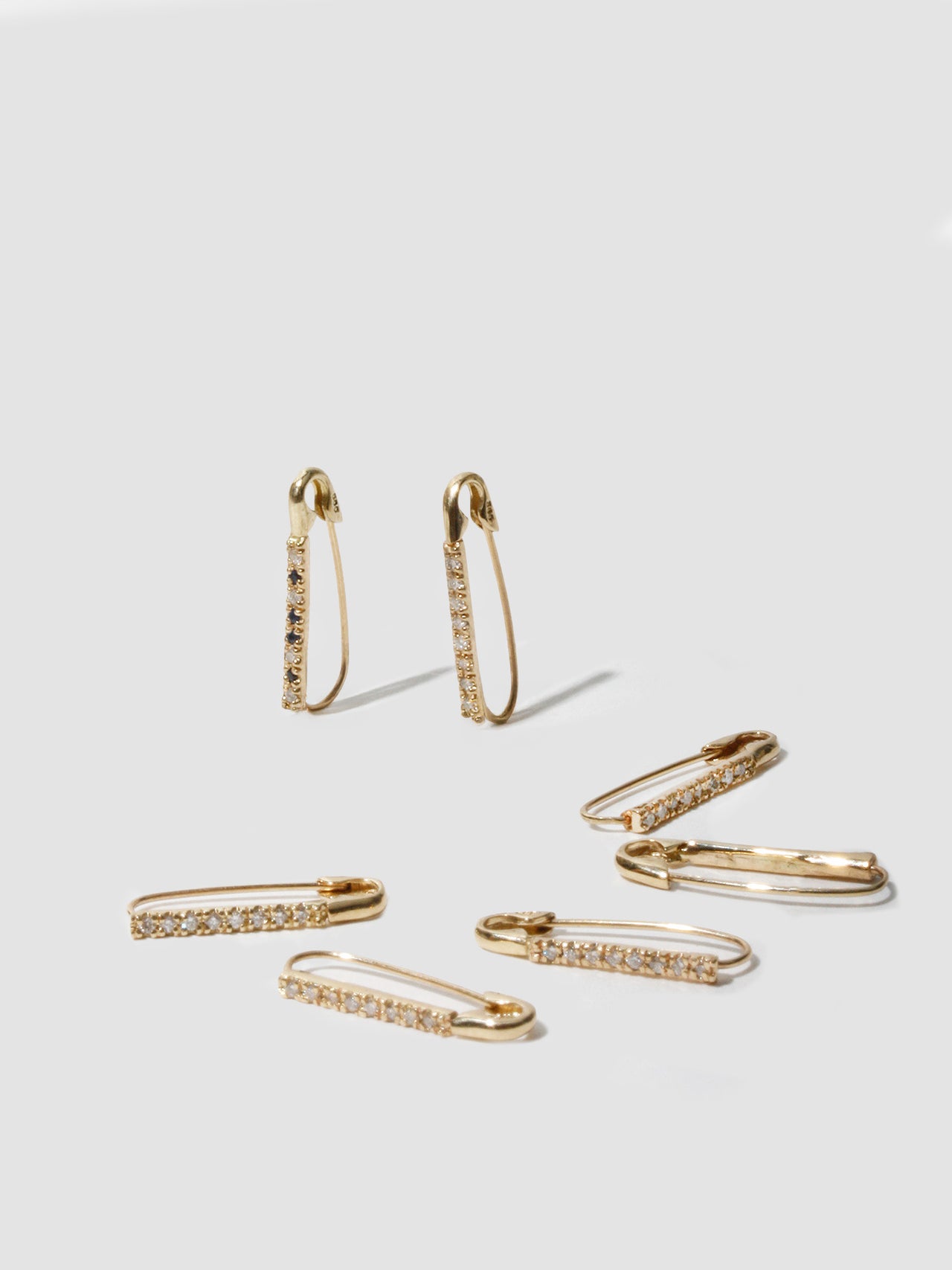 14kt Yellow Gold Mini Diamond Safety Pin pictured on light grey background. 