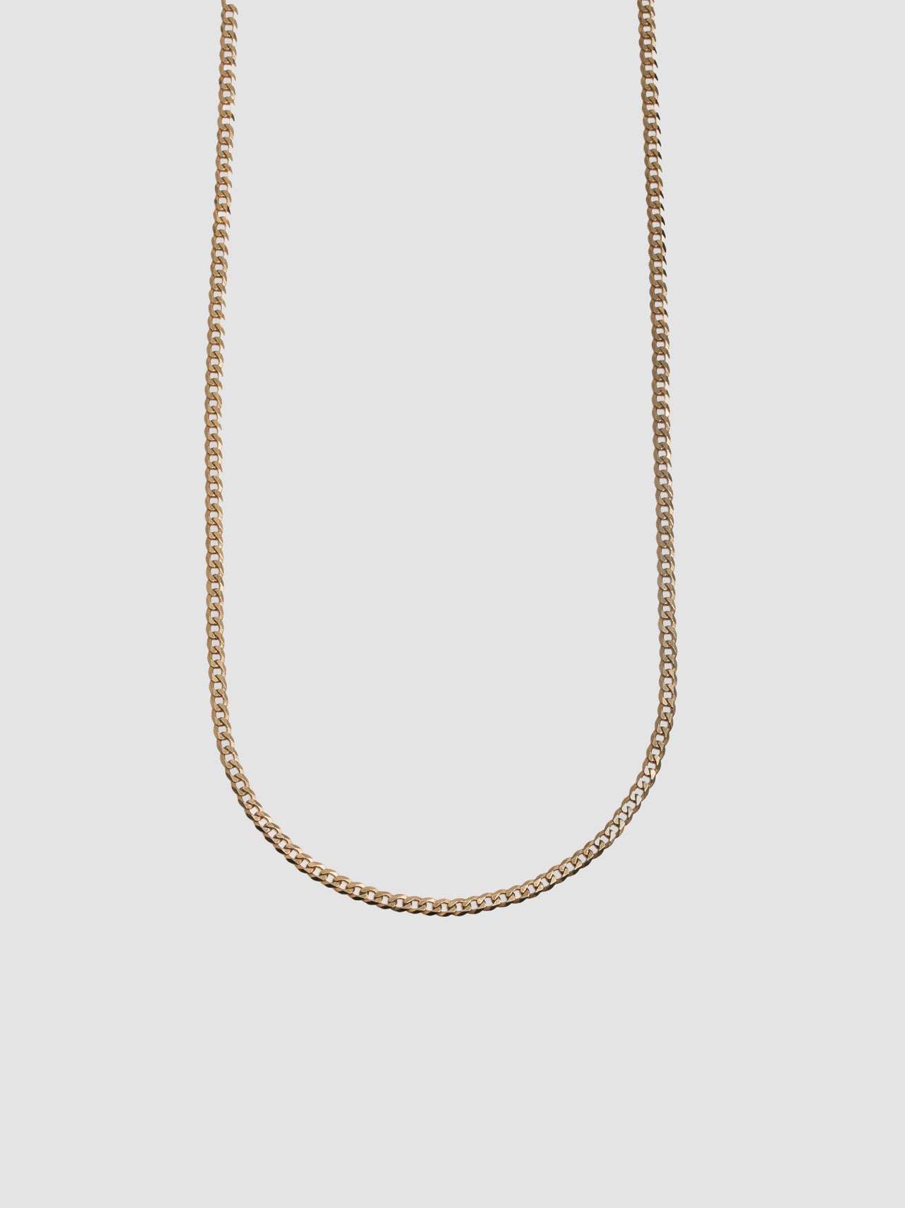 Gold chain necklace on a light gray background