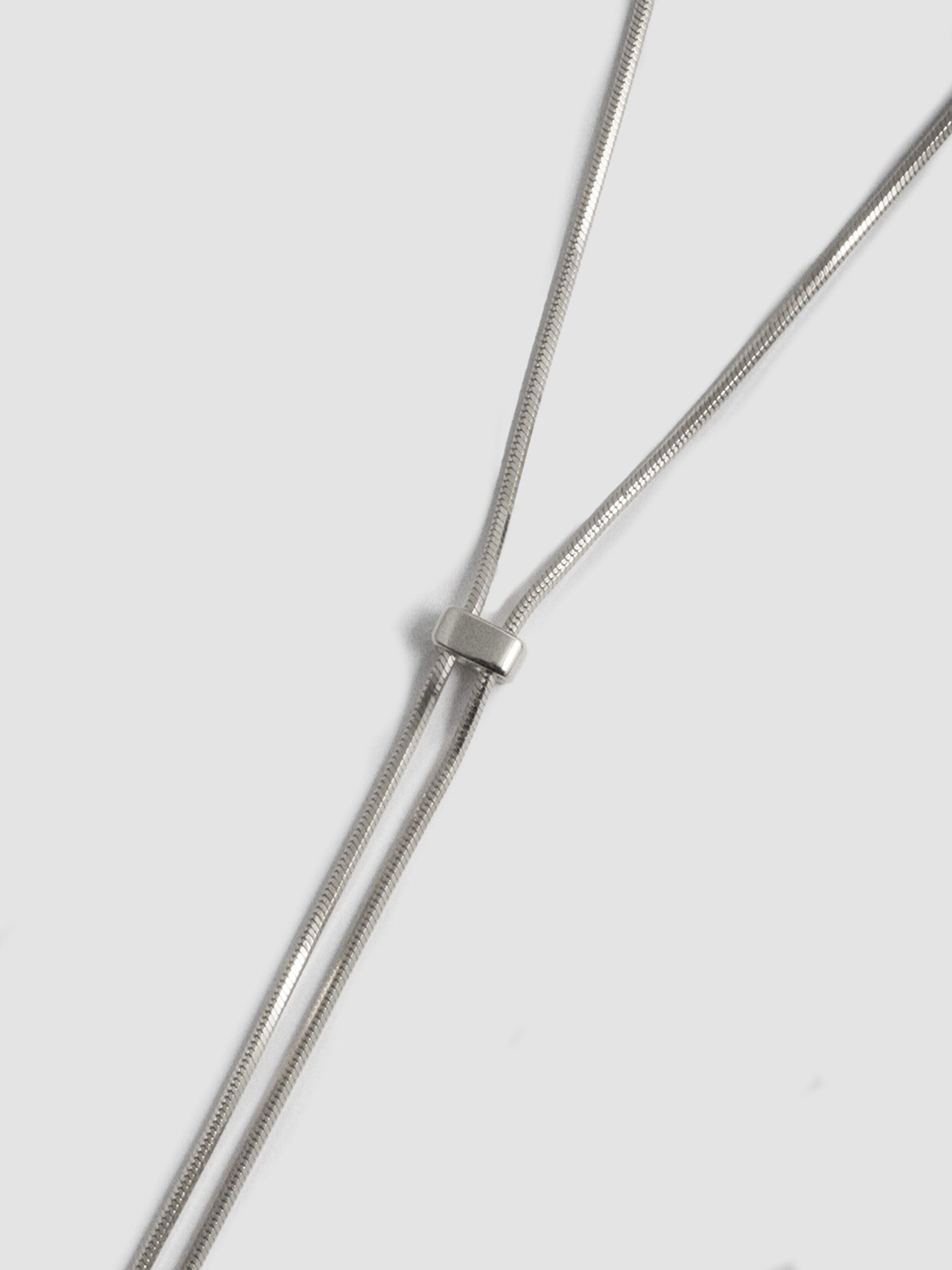 Close up shot of Sterling Silver Bolo Pendant Necklace on light grey background.