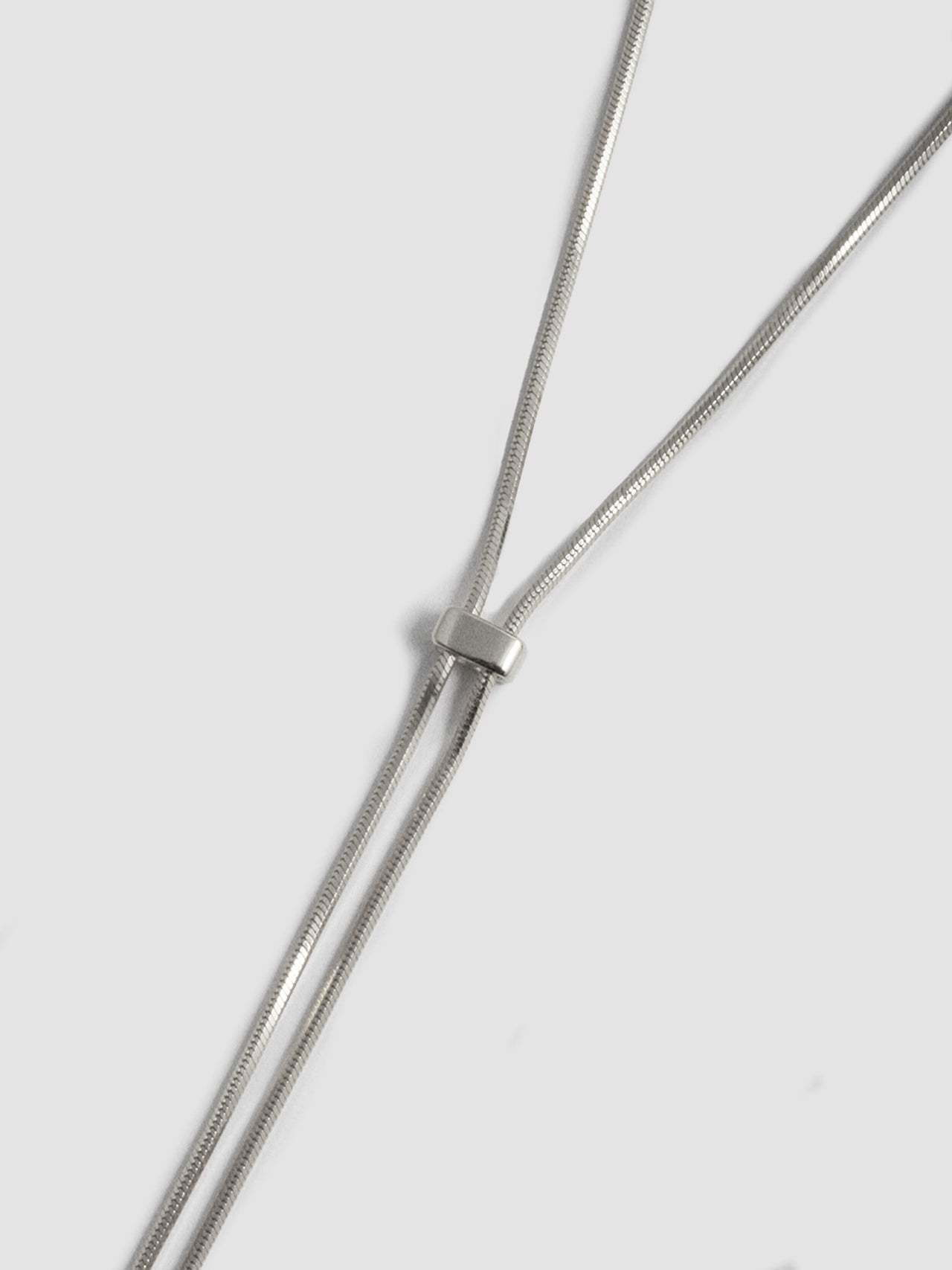 Close up shot of Sterling Silver Bolo Pendant Necklace on light grey background.