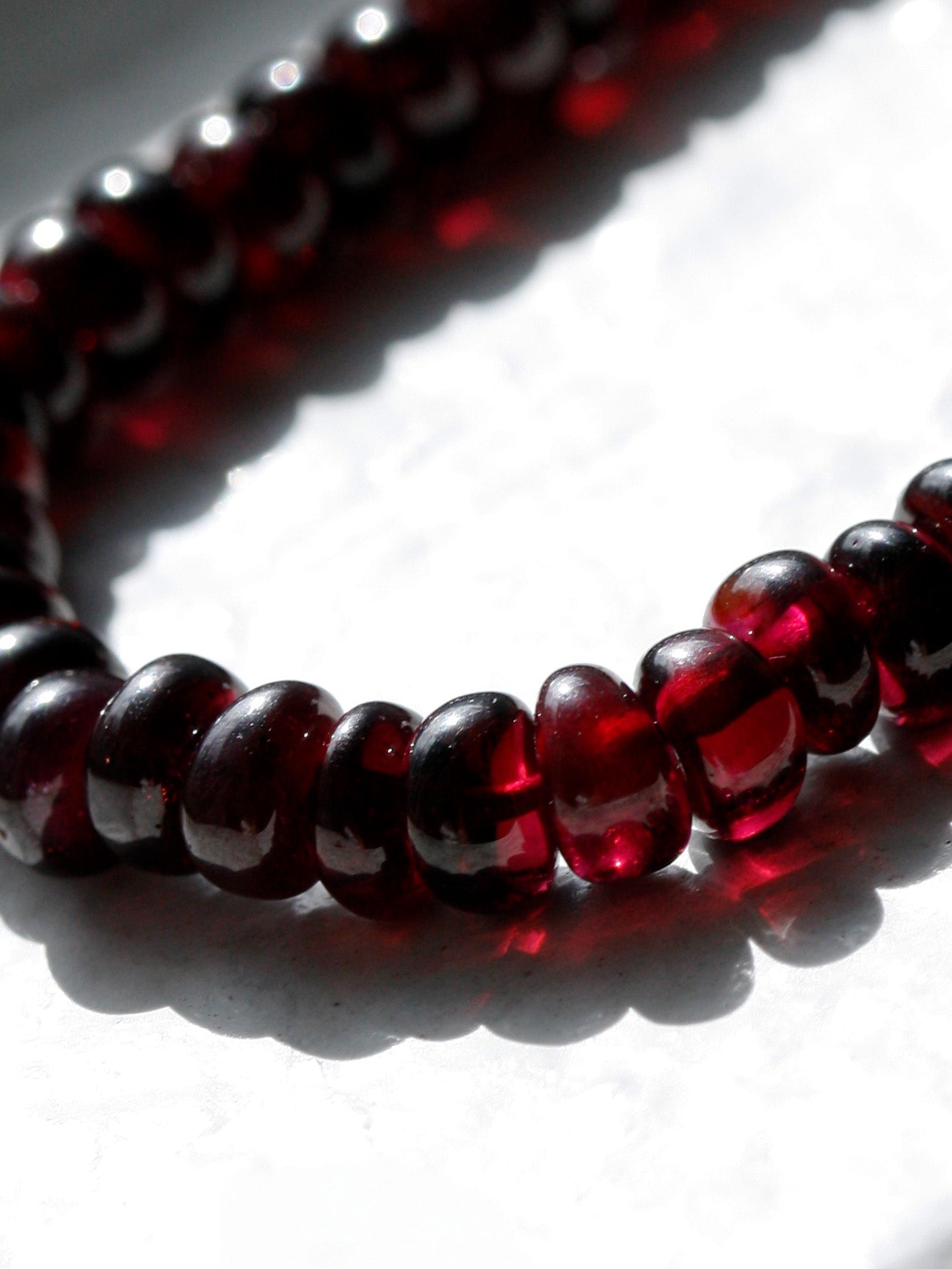 Close-up of a red beaded necklace on a white background