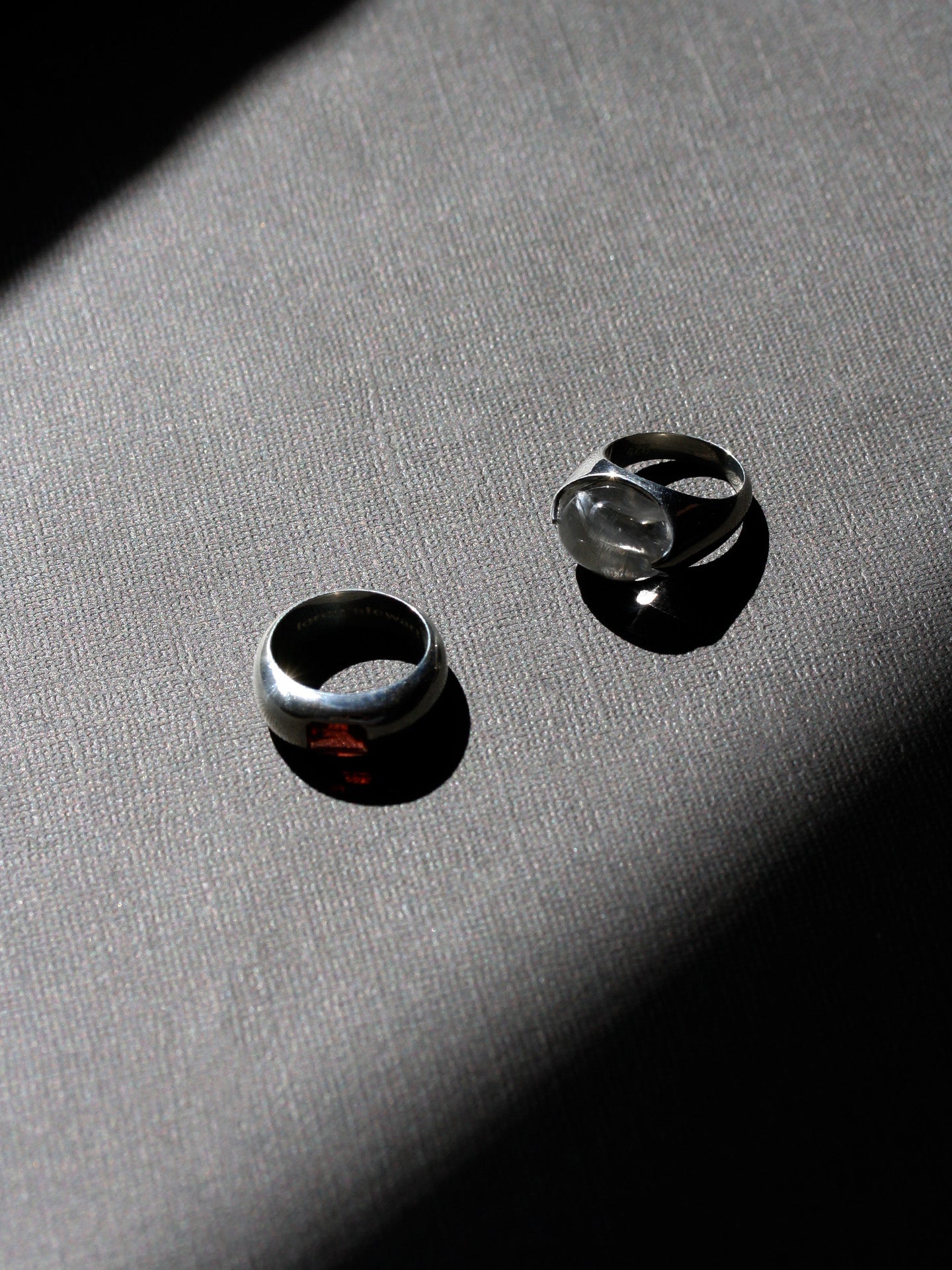 Two silver rings on a textured gray surface