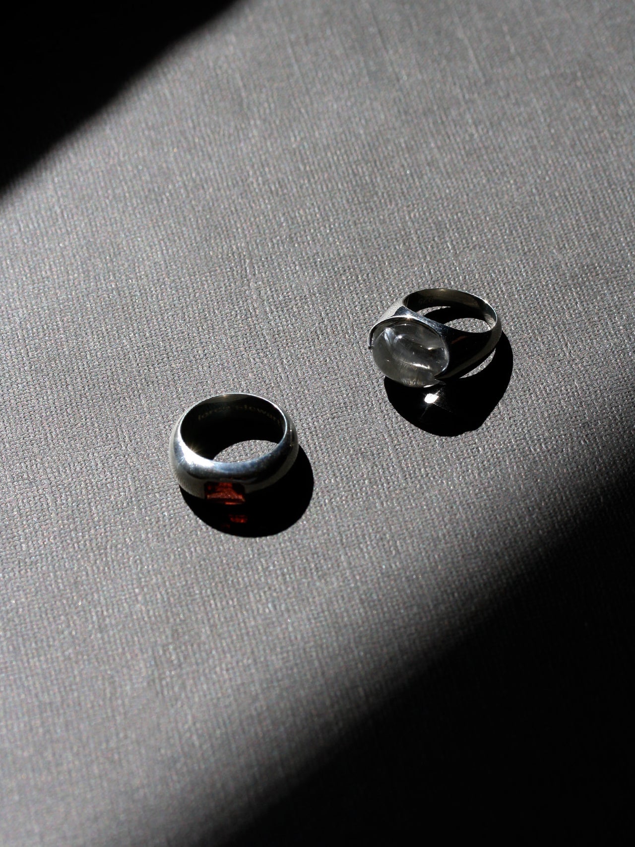 Two silver rings on a textured gray surface