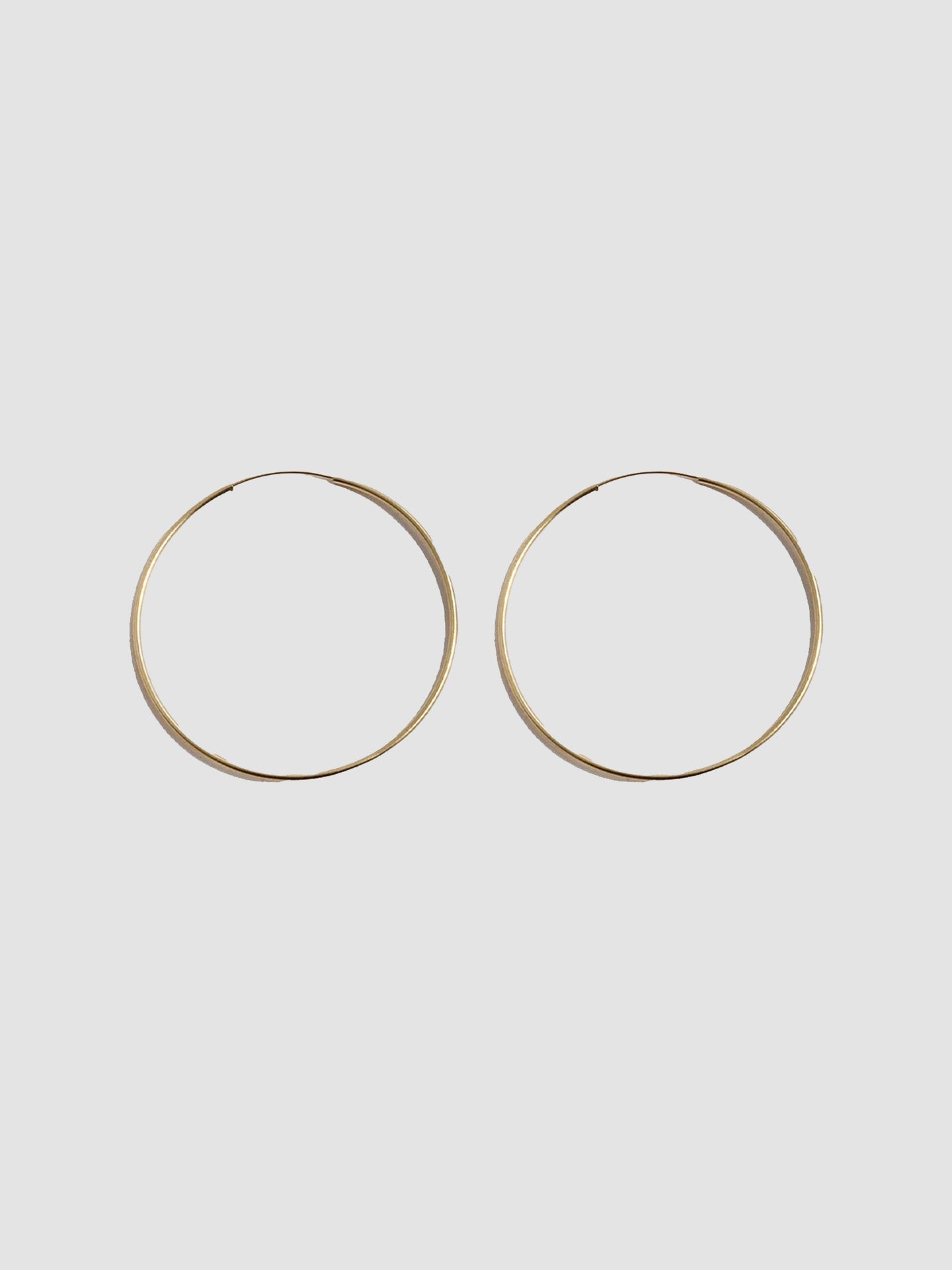 14kt Yellow Gold Ultralight Infinity Hoops  shot on light grey background.