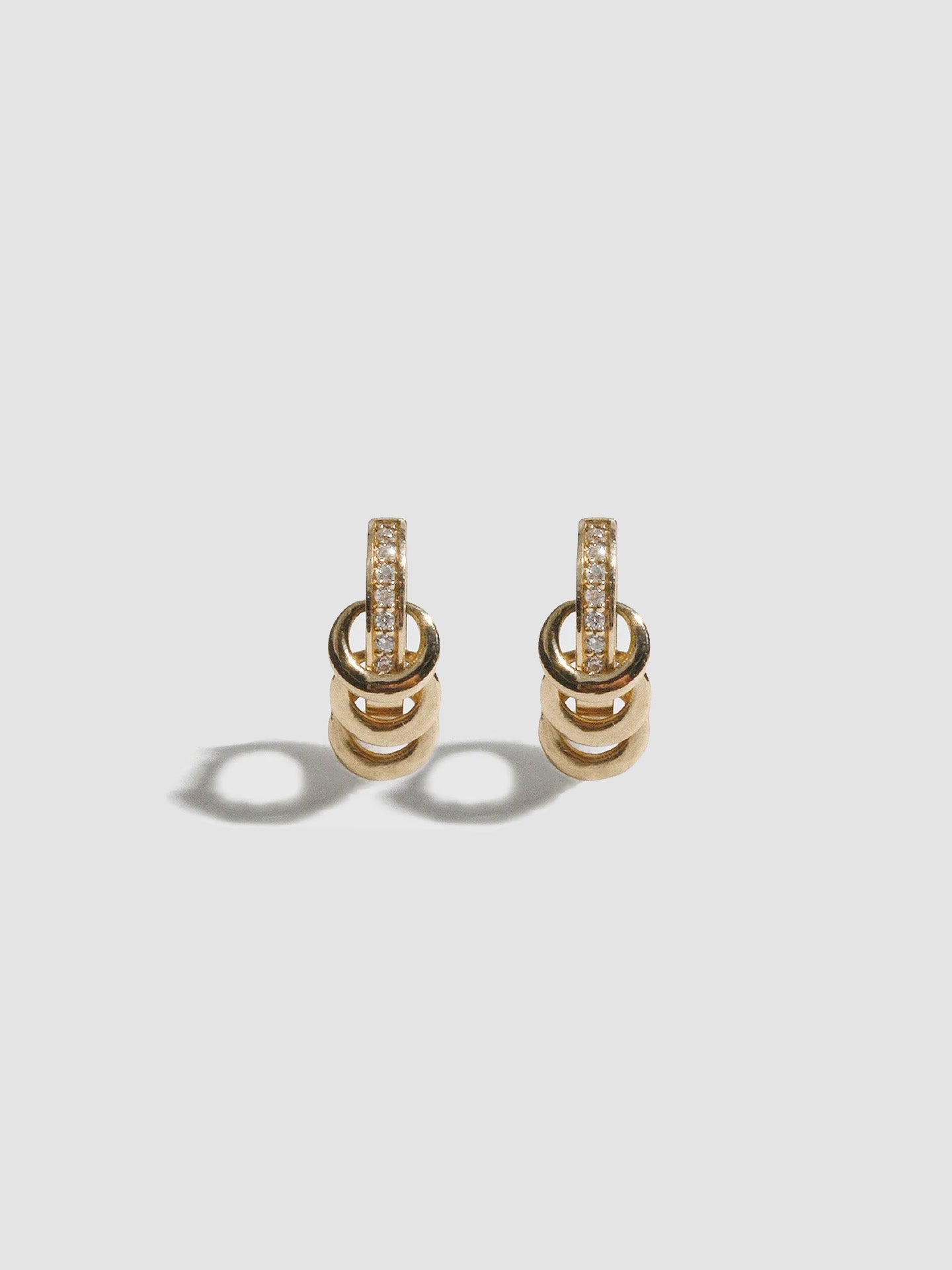 Pair of gold earrings with diamond accents on a light gray background