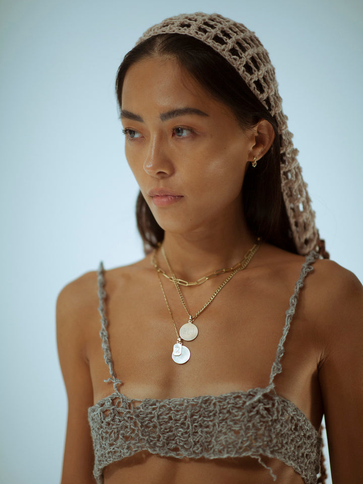 14Kt Yellow Gold Disk Pendant pictured on model. Hanging from chain along with other pendants.