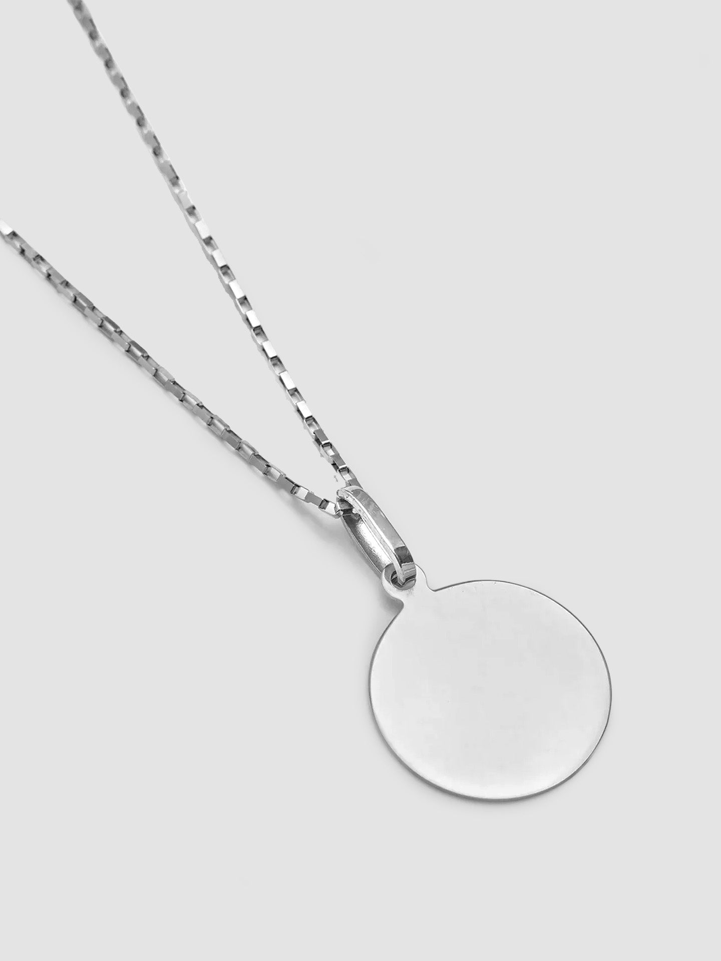 A sterling silver disk pendant attached to a silver chain, displayed against a white background.