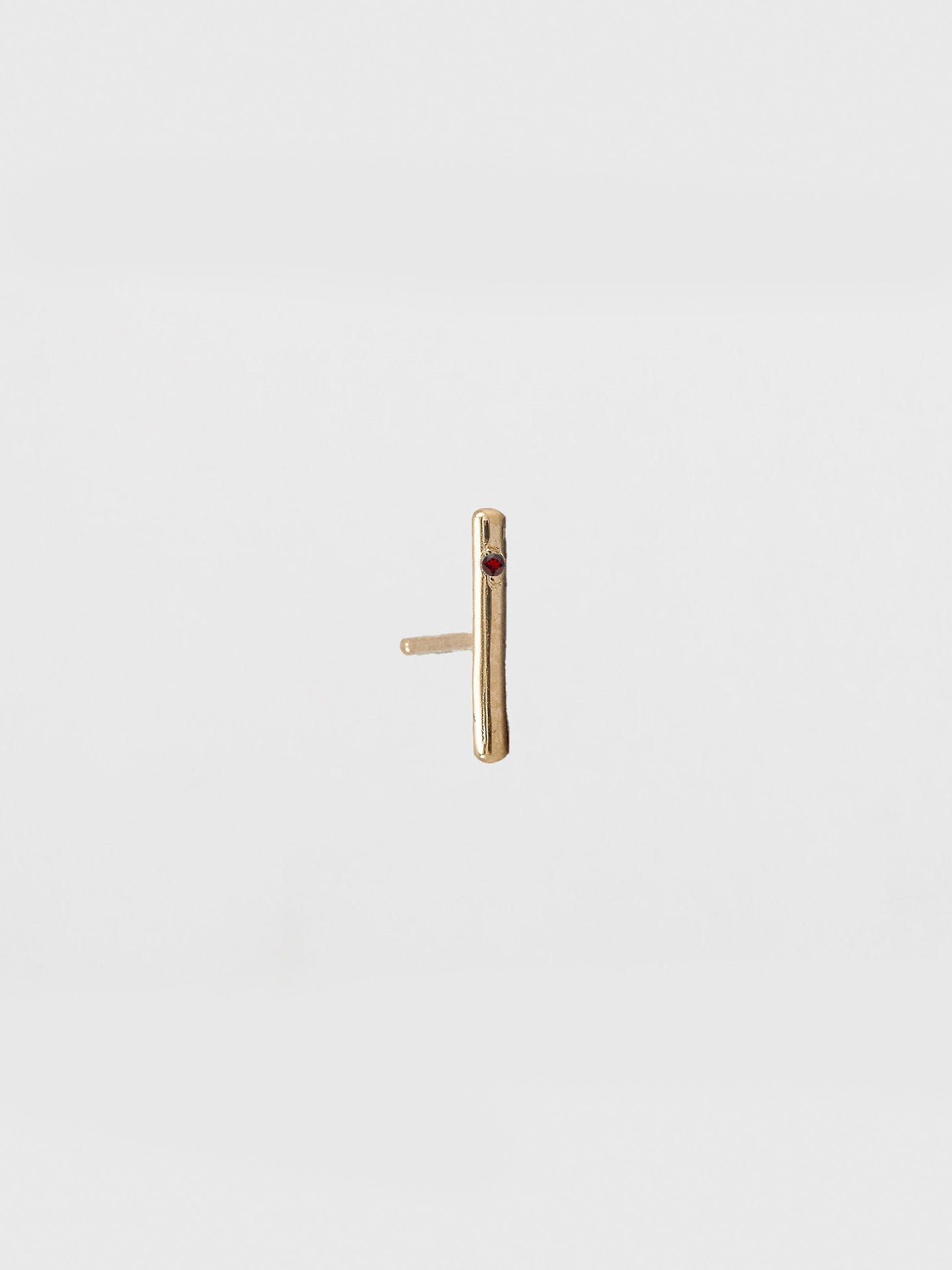 Gold bar earring on a light beige background