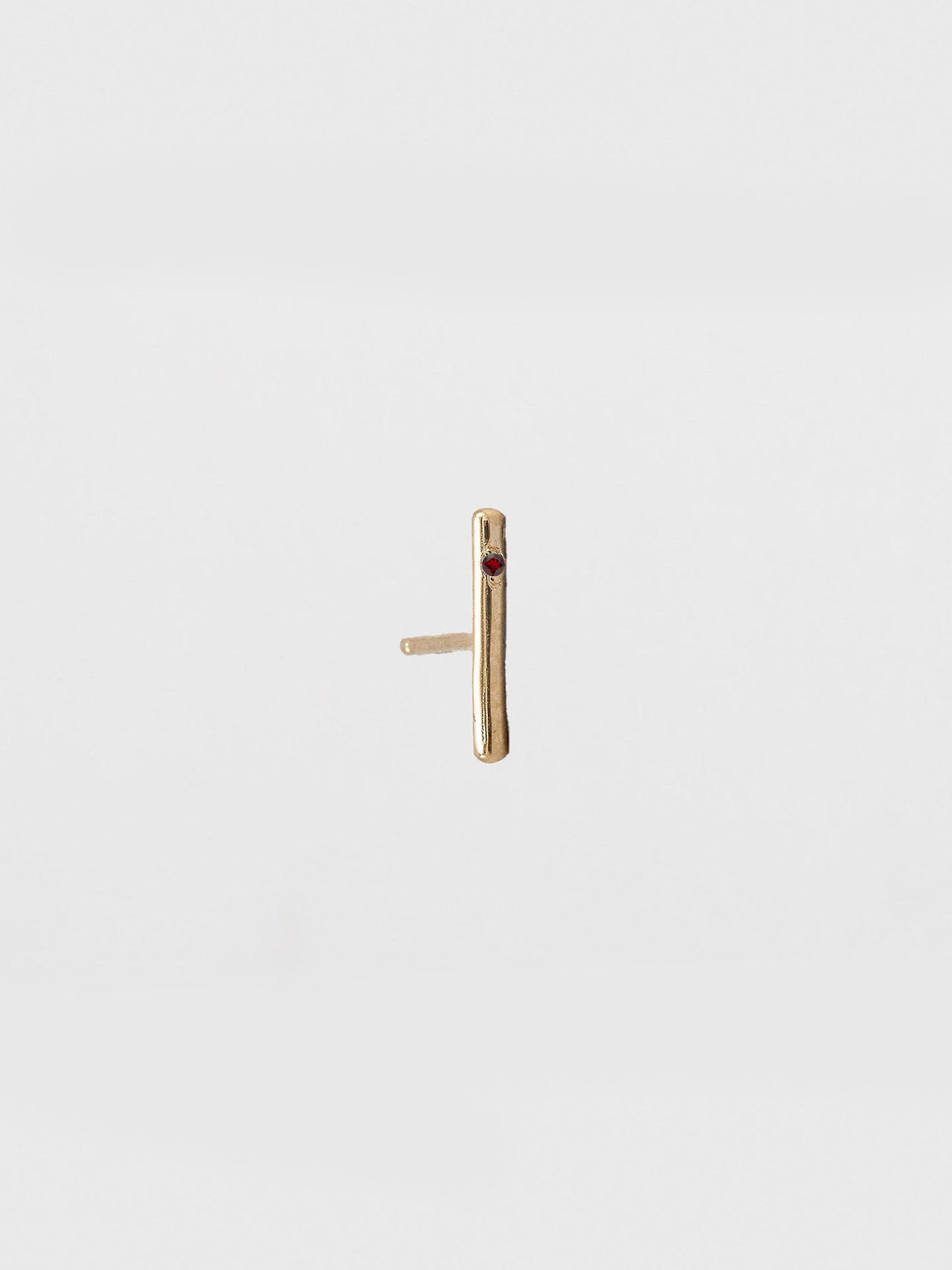 Gold bar earring on a light beige background