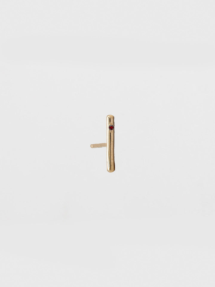Gold bar earring on a light beige background