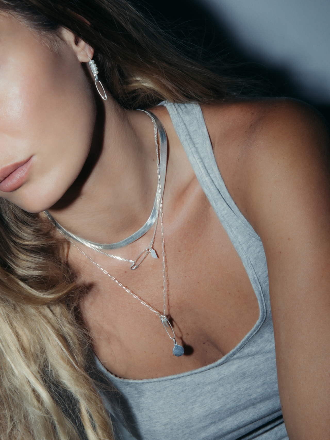 Sterling Silver Safety Pin Earring pictured as a charm holder and necklace extender. Model is wearing the Sterling Silver XL Herringbone Necklace (16"), Petite Havana Chain (18"), and the 