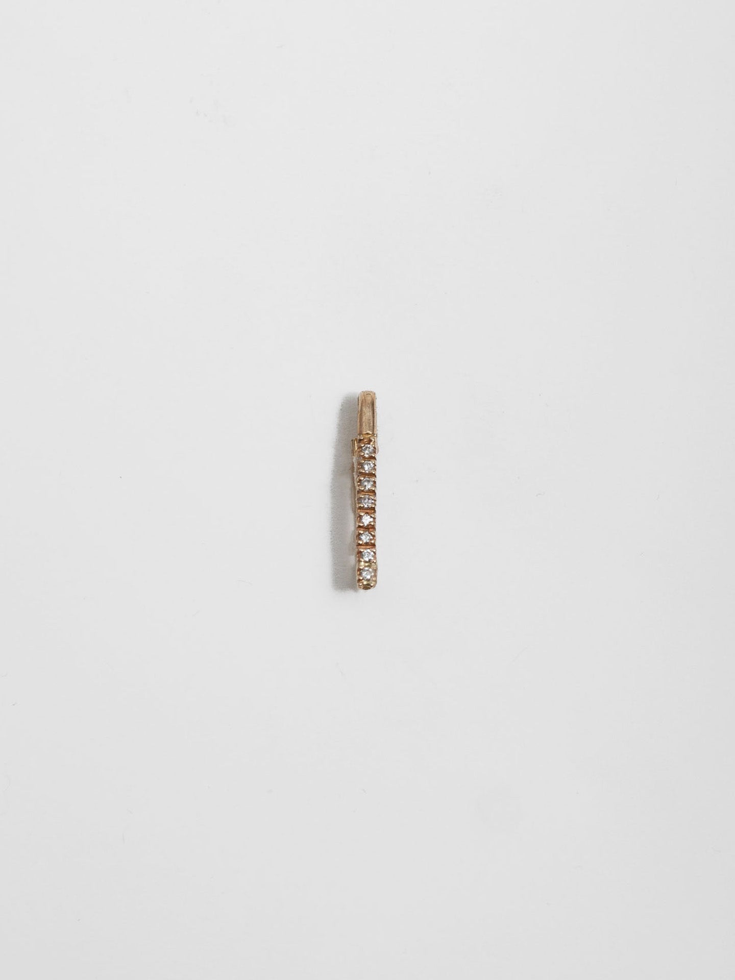 14kt Yellow Gold Mini Diamond Safety Pin pictured on light grey background.