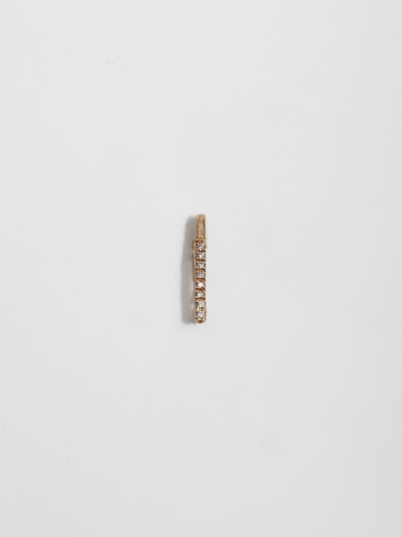 14kt Yellow Gold Mini Diamond Safety Pin pictured on light grey background.