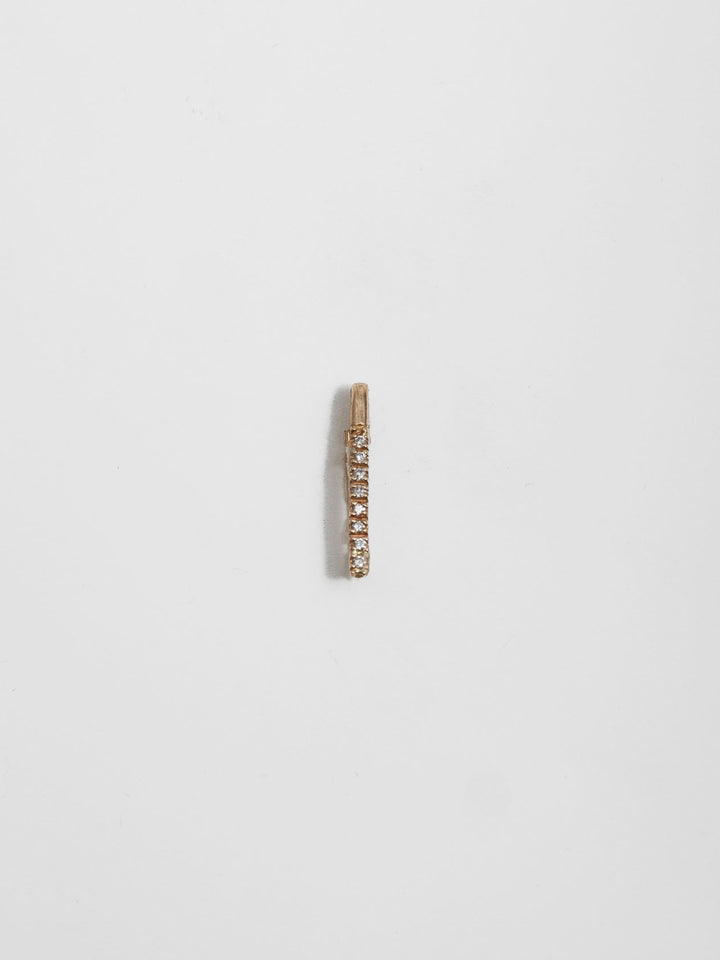 14kt Yellow Gold Mini Diamond Safety Pin pictured on light grey background.