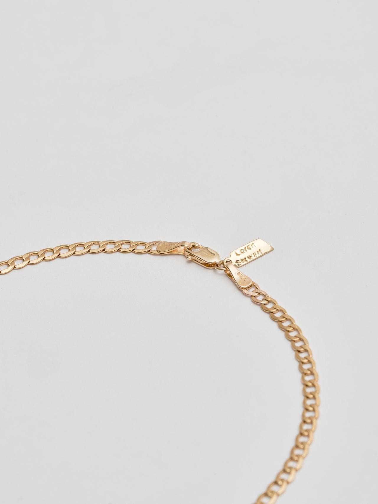 Close up of 14Kt Yellow Gold XL Lightweight Havana Chain Anklet pictured on light grey background. 