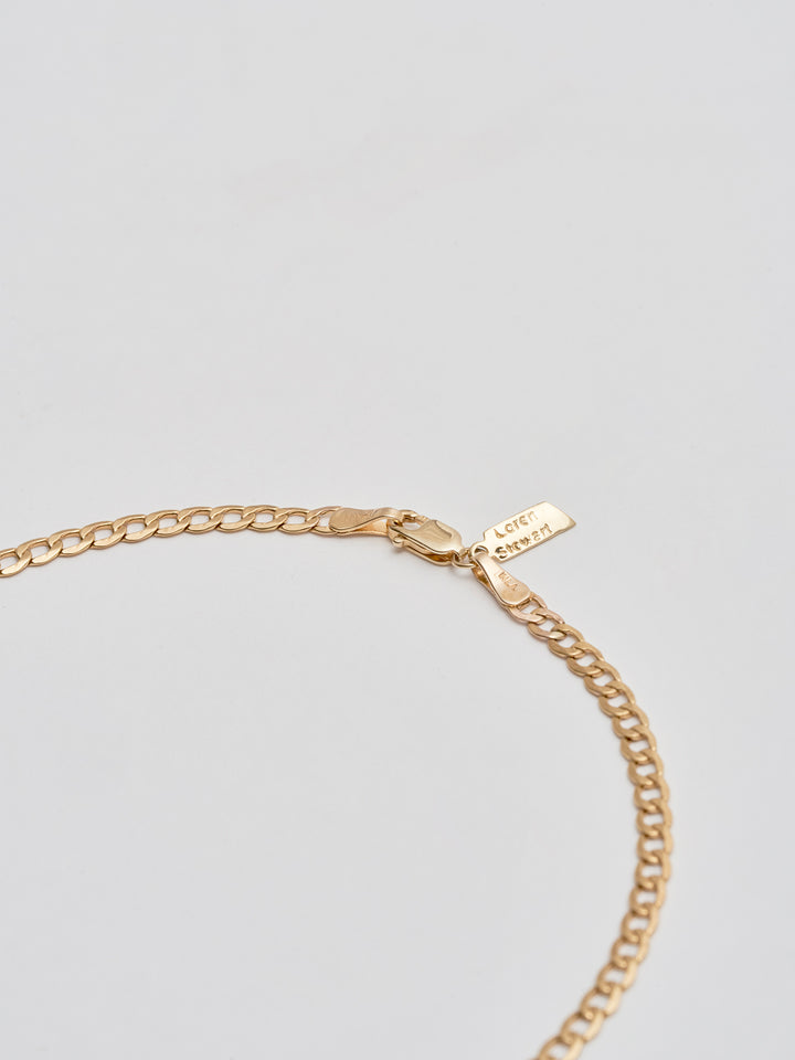 Close up of 14Kt Yellow Gold XL Lightweight Havana Chain Anklet pictured on light grey background. 