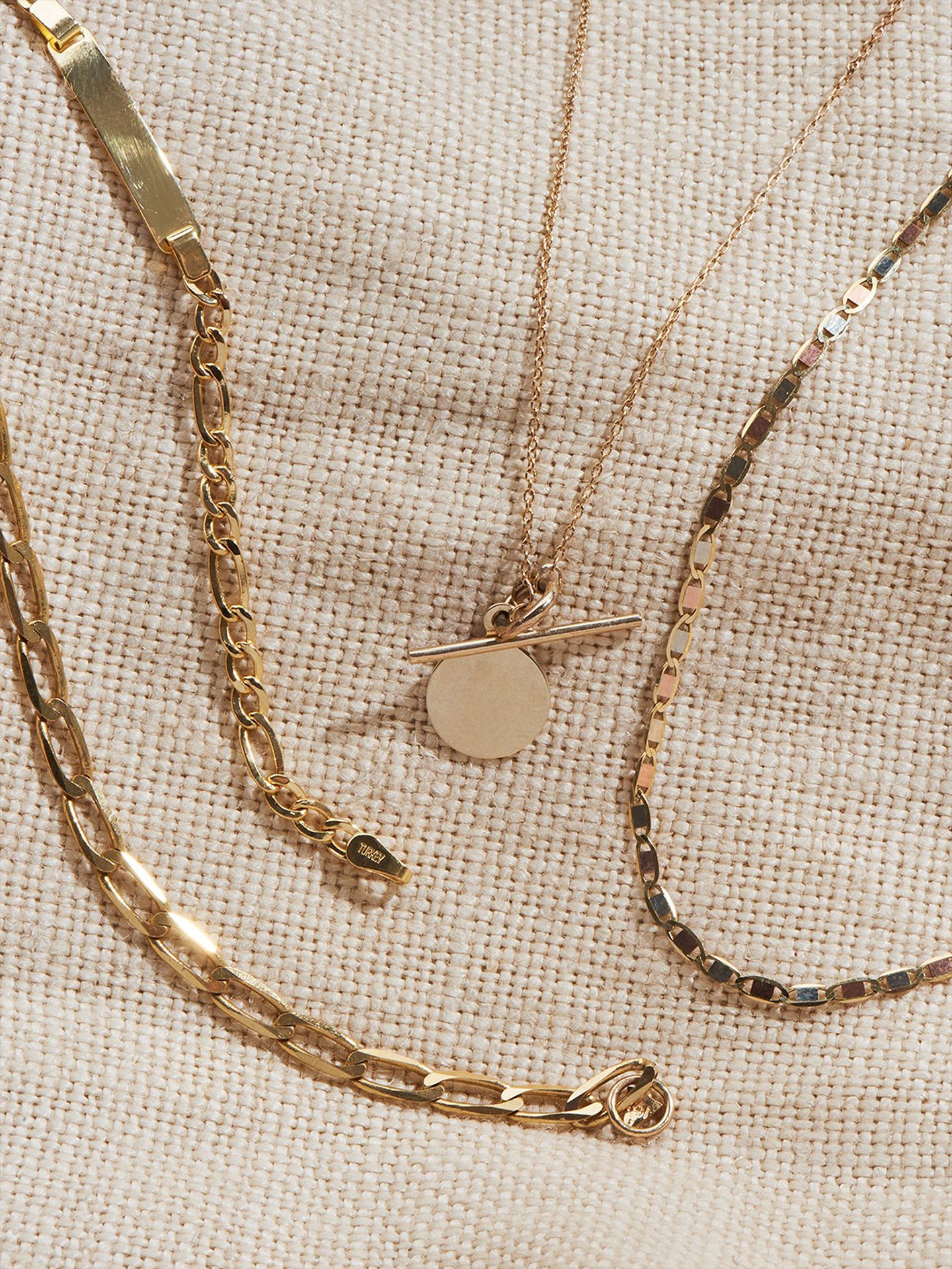 Mini Disk & Toggle Necklace shot on flat lay with other necklaces