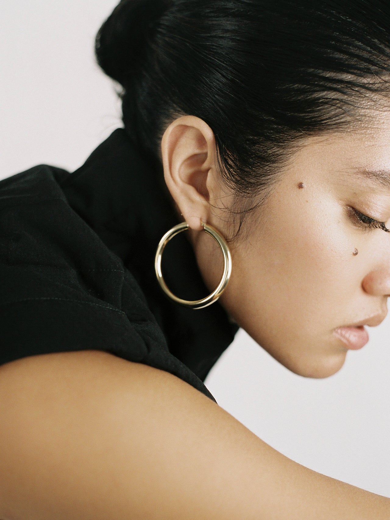 On model side profile shot of the Tru Hoops in Vermeil gold (Vermeil Hoops 49.5mm diameter 5mm thick) Background: Grey backdrop