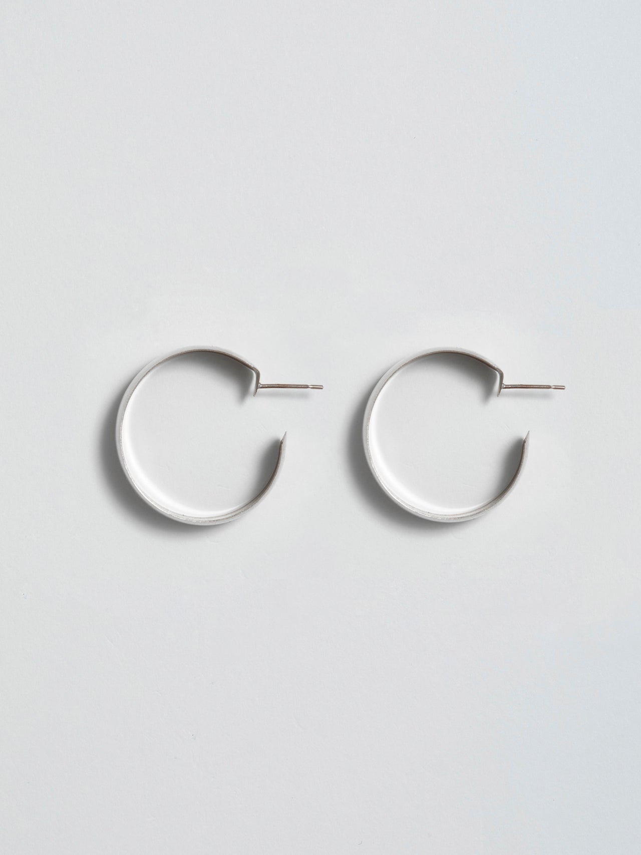 Product shot of the XL Dome Hoops(Sterling Silver Hoop Earrings 30mm Diameter 12mm Wide) Background: Grey backdrop