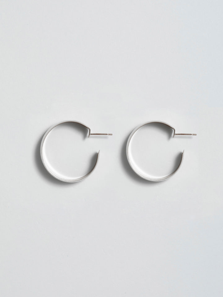 Product shot of the XL Dome Hoops(Sterling Silver Hoop Earrings 30mm Diameter 12mm Wide) Background: Grey backdrop